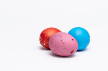 Three colored Easter eggs  on the white background  ready to be split to  friends and family for Easter. One of them is cracked and another one is broken
