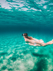 Woman swimming under water near a Boat