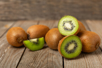 Kiwi on wooden background. Whole fruit and slices pieces of green kiwi on table. fresh ripe juicy kiwi. Tropical fruit. Organic fruit. Healthy eating. Space for text. Copy space.