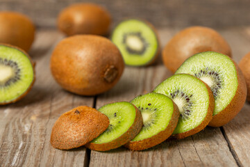Kiwi on wooden background. Whole fruit and slices pieces of green kiwi on table. fresh ripe juicy kiwi. Tropical fruit. Organic fruit. Healthy eating. Space for text. Copy space.