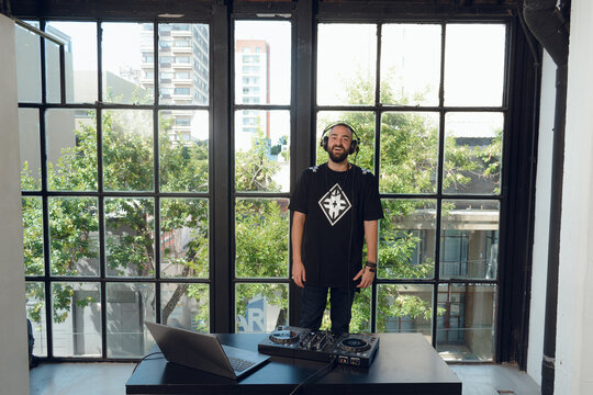 adult man in his studio standing in front of the dj set looking at the camera.