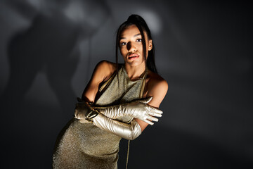 Fototapeta premium Elegant woman in gold attire showcases modern fashion trends in a stylish indoor setting