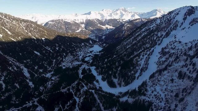 Aerial view of Champex Lac ski resort surrounded by snow-covered trees, alpine chalets, and a frozen lake, offering a tranquil winter holiday escape in Switzerland.