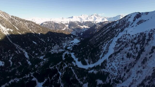 An aerial view of Champex Lac at dusk reveals a tranquil frozen lake, snow-covered chalets, and alpine forests, creating a peaceful winter retreat in the Swiss Alps.