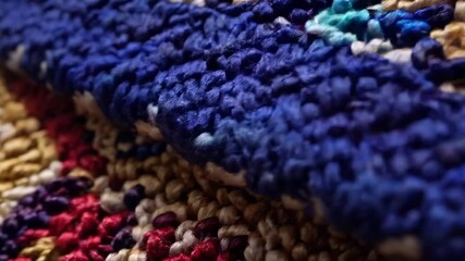 Close-up of a richly textured woven textile with red, blue, beige, and purple threads. - Powered by Adobe