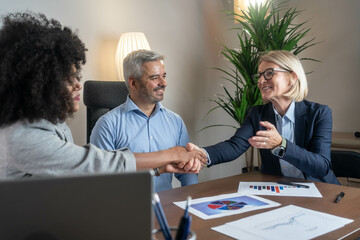 Happy mid aged business woman manager handshaking at office meeting. Smiling female hr hiring...