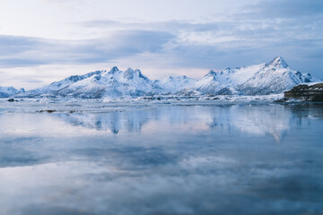Snowy mountains on coast of frozen sea at sundown