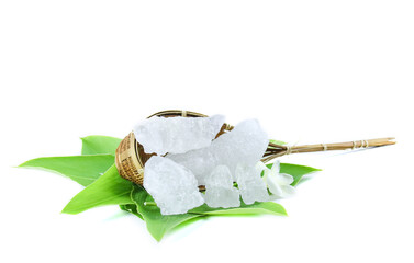 Pieces of alum stone on green leaf against white background. This image emphasizes the connection between natural minerals and plant based ingredients in traditional practices and holistic wellness.