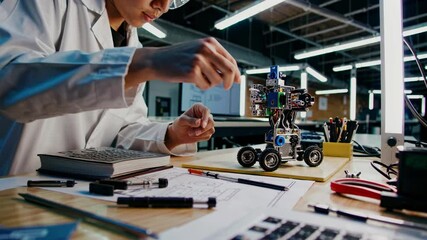 Young engineer builds a robot in a modern lab filled with technology and designs
