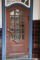 close-up of a very old wooden door with many small windows and a metal handle and blue wooden frame of an old building