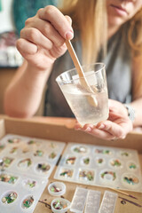 Adult caucasian female crafting resin molds with wooden stick in studio setting.