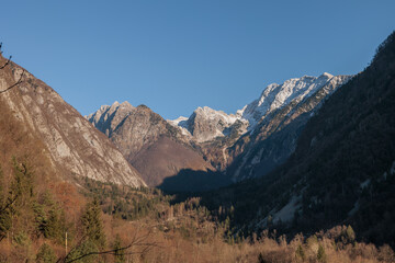 vista panoramica di un ambiente naturale tra le montagne della Slovenia nord-occidentale, di giorno, al tramonto, in inverno, con cielo sereno