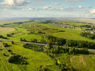 Empty roadway surrounded by green trees and planted fields