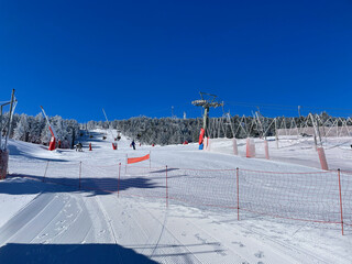 Skiers slalom down a snowy slope at the Valdelinares ski resort in sunny weather during winter