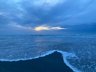 Merging waves at dusk on a winter beach