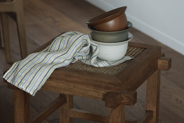 Set of ceramic bowls with linen towel on rattan stool