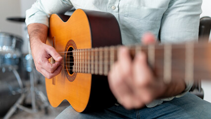 Close-up of an Unrecognizable Man Playing an Acoustic Guitar, focusing on his hands and the...
