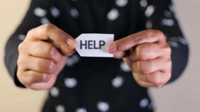 Individual displays a help sign, conveying a message of need or support in a moment of struggle.