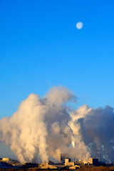 Factory or Energy Plant Emitting Pollution and smoke into the air with moon in blue sky