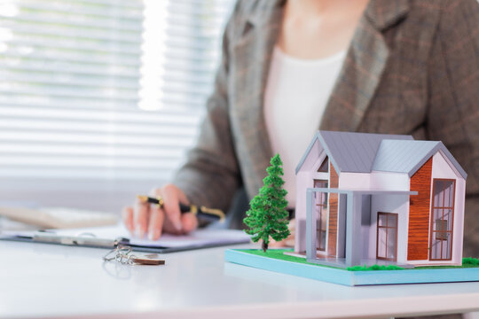 Asian real estate business owner showing off a house model, taking individual notes Real estate agents who present home designs to potential clients.