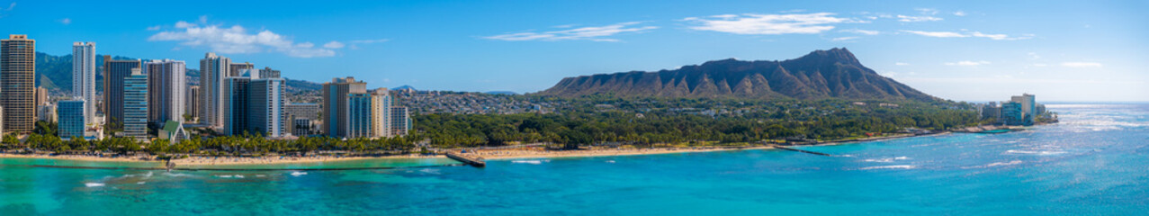 Obraz premium Aerial view of Waikiki Beach in Honolulu, Oahu, Hawaii, featuring high rise buildings, turquoise waters, sandy shores, and Diamond Head Crater.