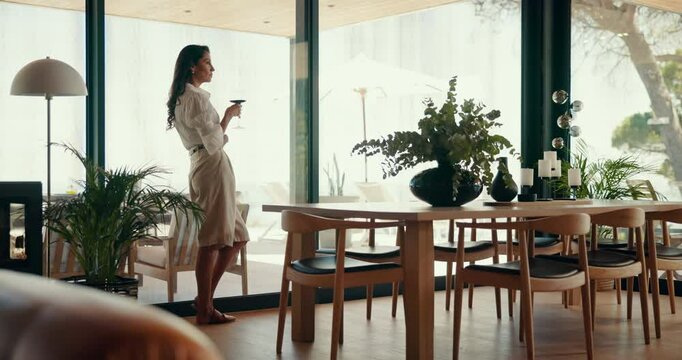 Peace, woman and drink wine in home for relax, thinking or calm by window view for reflection. Alcohol glass, living room and person with beverage, dream or remember memory on weekend in luxury house