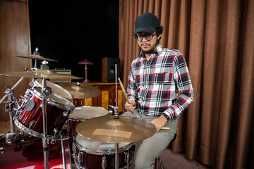 Drummer Playing Red Drum Set in Rehearsal Room