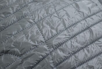 A close-up of a smooth, gray fabric with a tightly woven pattern. The material has a glossy finish and is likely used for outdoor gear such as jackets or backpacks due to its durability