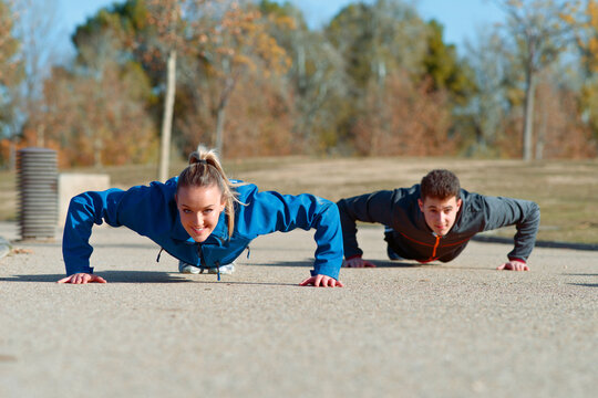 Fitness enthusiasts performing push ups in outdoor setting