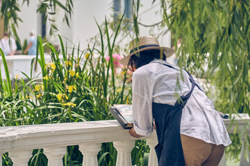 An unrecognizable woman is engaged in her hobby, painting against the background of nature. Creates...