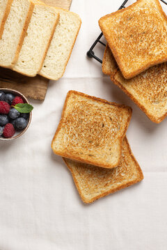 Toasts and fresh berries on wooden board and cloth