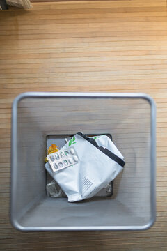 View from above of waste in a trash bin on wooden floor