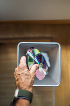Hand Disposing of DVDs Into a Trash Bin From Above