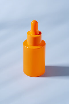 Bright orange serum bottle on a plain background