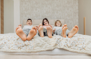 the bare, clean feet of two children, offspring, lying side by side under the same blanket on the...