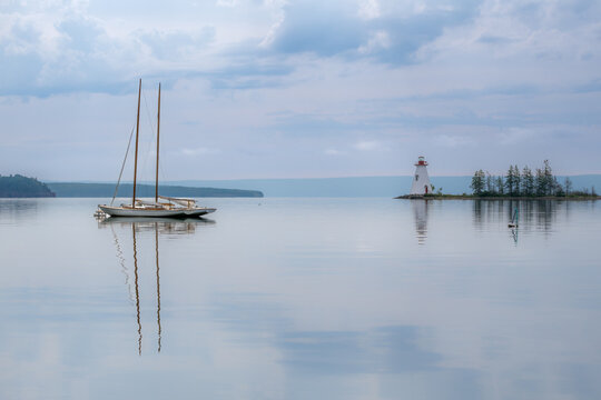 Two moored sailboats and Kidston Island Lighthouse in Baddeck, Nova Scotia, Canada