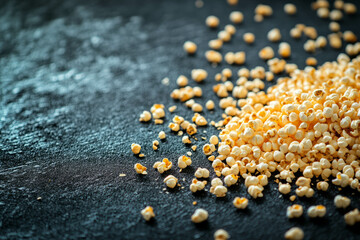 Popcorn kernels scattered dramatically on a textured dark surface with reflections