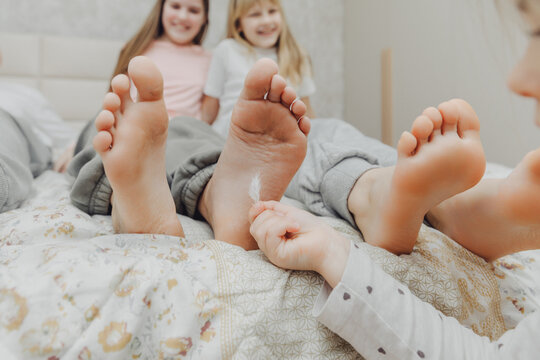 children tickle each other's heels with a feather