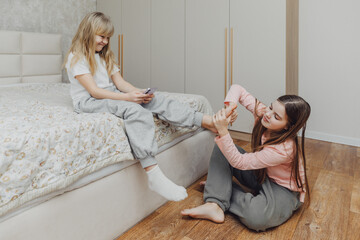 the children are wrapped in a blanket and tickling each other's heels on the bed. Family having fun...
