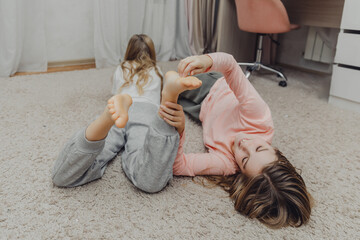 the children are wrapped in a blanket and tickling each other's heels on the bed. Family having fun...