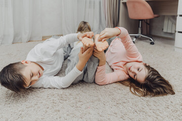 the children are wrapped in a blanket and tickling each other's heels on the bed. Family having fun...