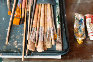Set of Used Paintbrushes and Tubes on an Artist’s Table