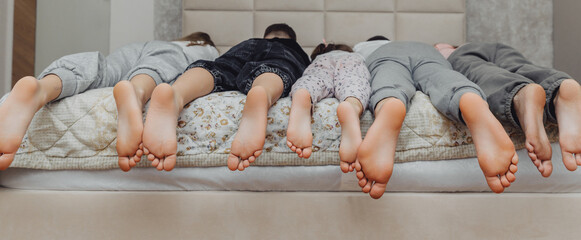 the bare, clean feet of two children, offspring, lying side by side under the same blanket on the...