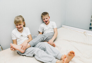 the children are wrapped in a blanket and tickling each other's heels on the bed. Family having fun...
