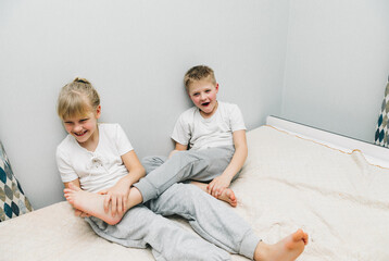 the children are wrapped in a blanket and tickling each other's heels on the bed. Family having fun...