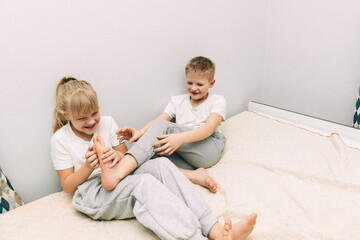 the children are wrapped in a blanket and tickling each other's heels on the bed. Family having fun...