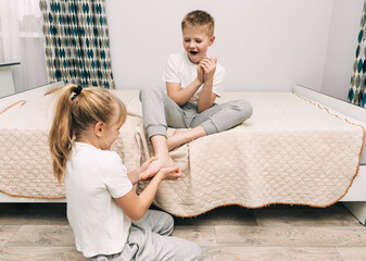 the children are wrapped in a blanket and tickling each other's heels on the bed. Family having fun...