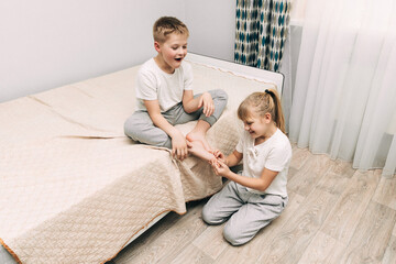 the children are wrapped in a blanket and tickling each other's heels on the bed. Family having fun...