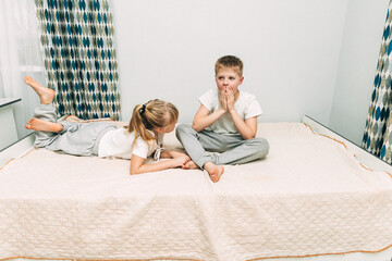 the children are wrapped in a blanket and tickling each other's heels on the bed. Family having fun...
