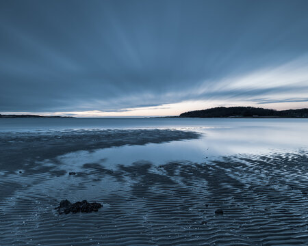 Coastal scenery near Gothenburg showcases tranquil waters and beautiful cloud formations at dusk